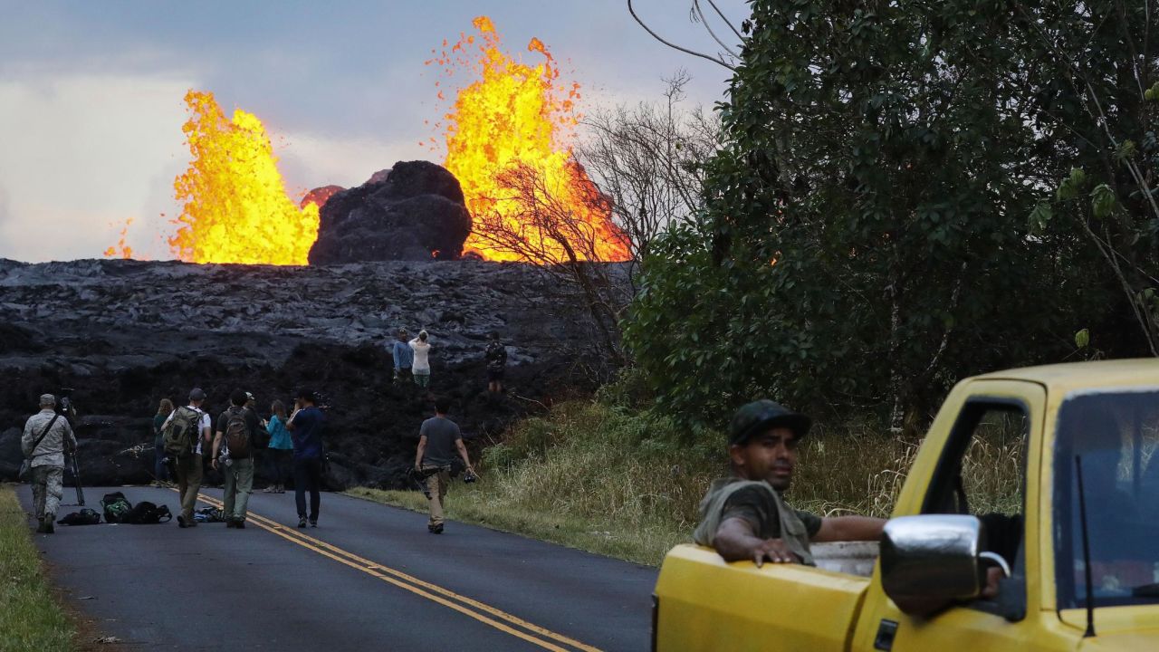 PAHOA, HI - MAY 26:  Onlookers and media gather as lava from a Kilauea volcano fissure erupts in Leilani Estates, on Hawaii's Big Island, on May 26, 2018 in Pahoa, Hawaii. The Big Island, one of eight main islands that make up Hawaii state, is struggling with tourist bookings following the Kilauea volcano eruptions, with summer bookings down 50 percent. Officials stress that the eruptions have thus far only affected a small portion of the island. Visitors spent $2.4 billion at the island in 2017. (Photo by Mario Tama/Getty Images)