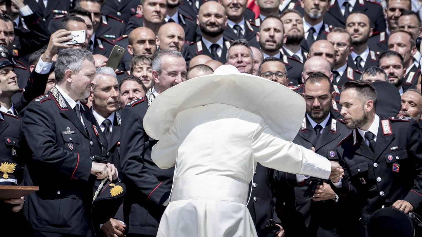 A gust of wind catches Pope Francis' mantle as he greets military police at the Vatican on Wednesday, May 30. 