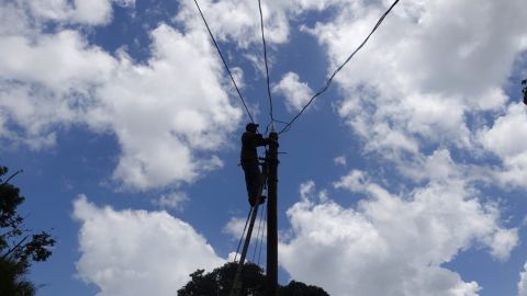 Charley Reyes works to restore power in the Paso Palmas community of Utuado.