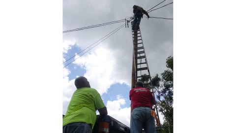 Neighbors from Paso Palmas community use old power lines found on the side of the road and splice them together to run new lines of power.