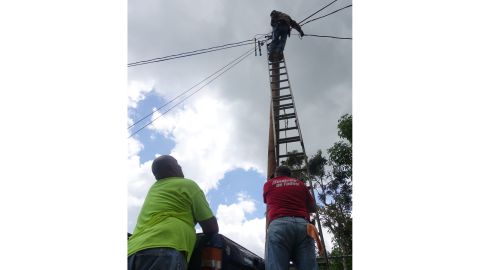 Neighbors from Paso Palmas community use old power lines found on the side of the road and splice them together to run new lines of power.
