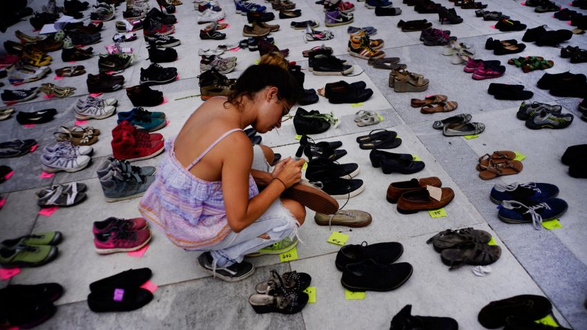 A woman places one of the hundreds of shoes in memory of those killed by Hurricane Maria in front of the Puerto Rico Capitol, in San Juan, Friday, June 1, 2018.  Puerto Rico's Institute of Statistics announced that it has sued the U.S. territory's health department and demographic registry seeking to obtain data on the number of deaths following Hurricane Maria as a growing number of critics accuse the government of lacking transparency. (AP Photo/Ramon Espinosa)