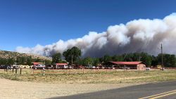 A plume of smoke from a wildfire rises behind Philmont Scout Ranch, Friday, June 1, 2018, near Cimarron, N.M. A wildfire raced across a swath of tinder-dry forest in northeastern New Mexico on Friday, sending up a thick plume of smoke that forced residents to flee their homes as heat and wind threatened to drive the flames. (Marty Mayfield/KRTN Radio via AP)