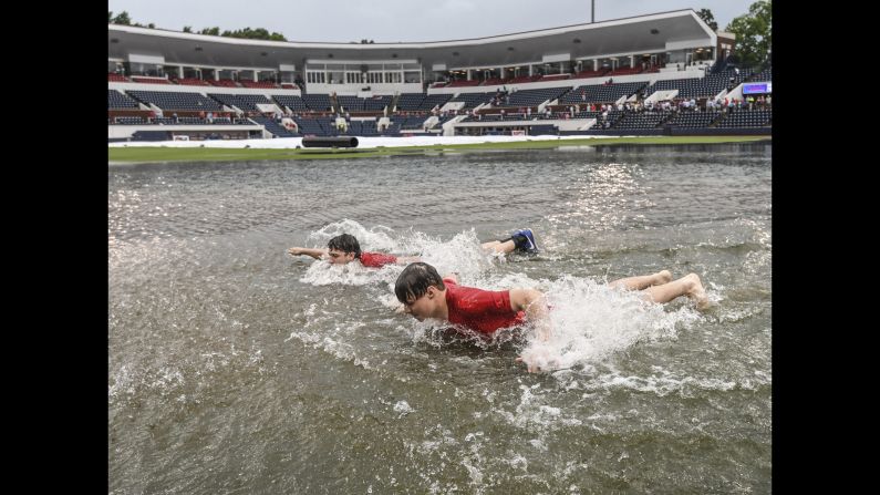 Jack Burkes, foreground, and Cole Catalano swim in the water in the outfield following heavy rainfall before the start of the Missouri State-Tennessee Tech NCAA college baseball regional tournament game in Oxford, Missouri on Friday, June 1.