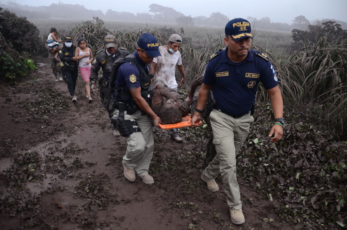 Police officers carry a wounded man after the eruption of the Fuego Volcano, in El Rodeo village.