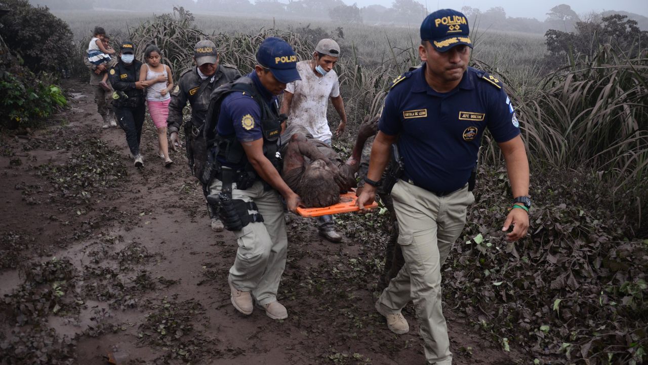 Police officers carry a wounded man after the eruption of the Fuego Volcano, in El Rodeo village.