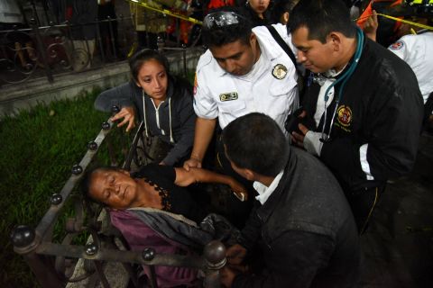 A woman is cared for by firefighters after she learned that a relative was among the victims in Alotenango.