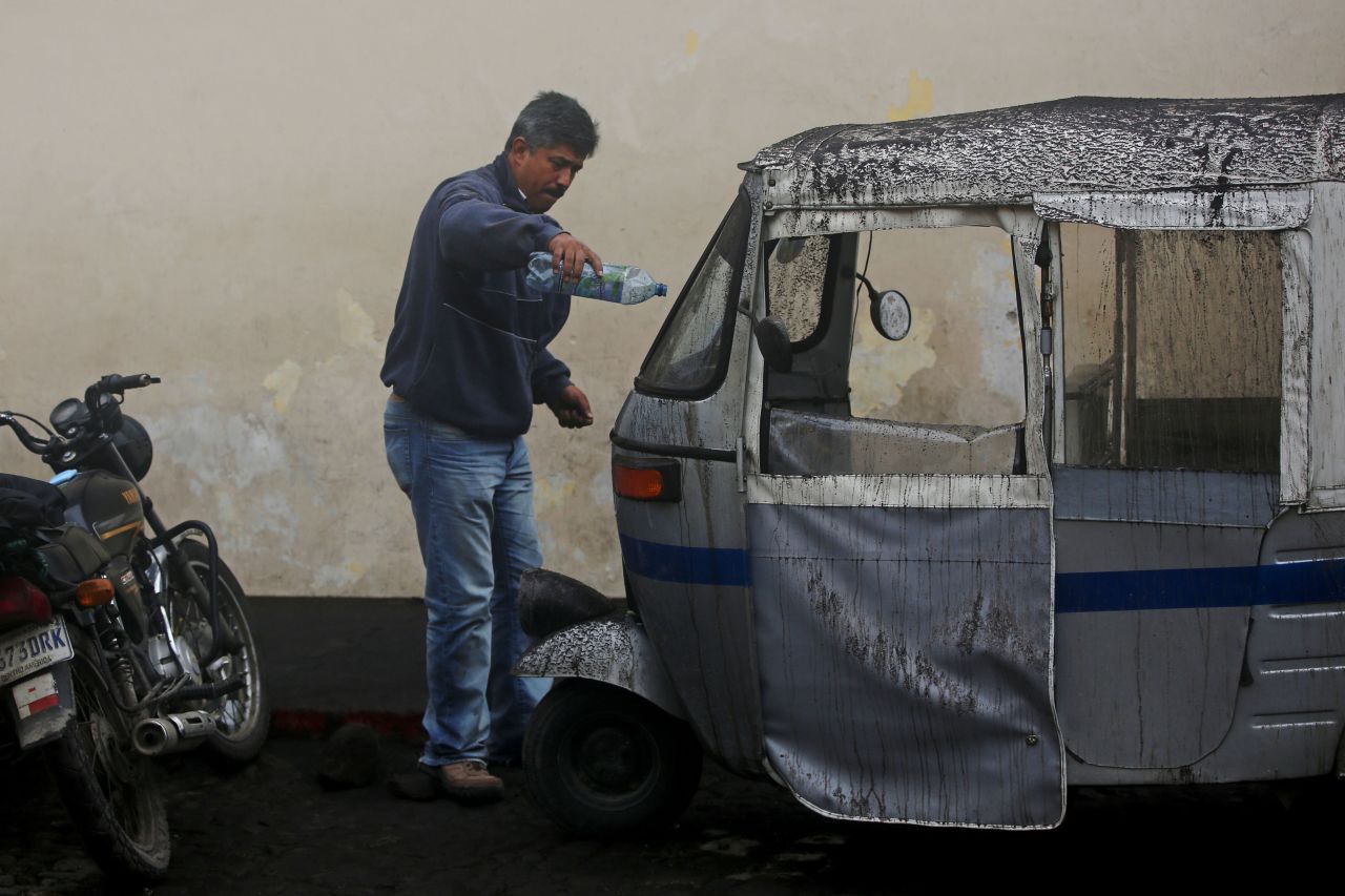 A man cleans his motorcycle taxi, which was covered in ash in Antigua.