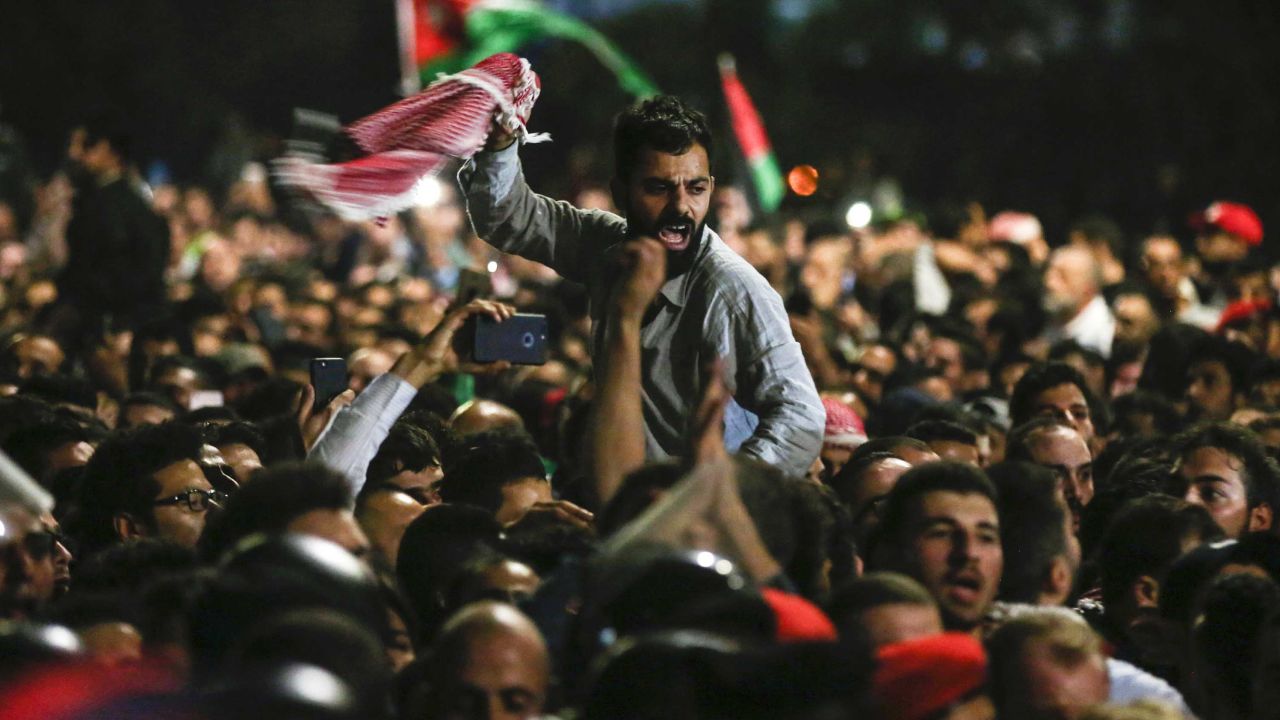 Jordanian protesters shout slogans and raise a national flag during a demonstration outside the Prime Minister's office in the capital Amman late on Friday. 