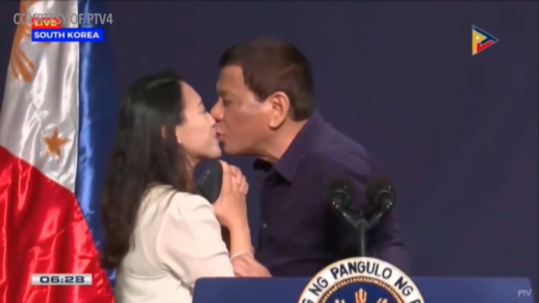 Philippines President Rodrigo Duterte kissing a Filipino woman on stage during a visit to South Korea in 2018. 