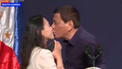 Philippines President Rodrigo Duterte kissing a Filipino woman on stage during a visit to So
