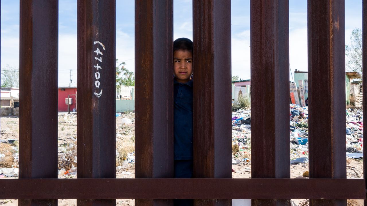 A young boy peers from the Mexican side of the US-Mexico border fence in Anapra, Texas.
