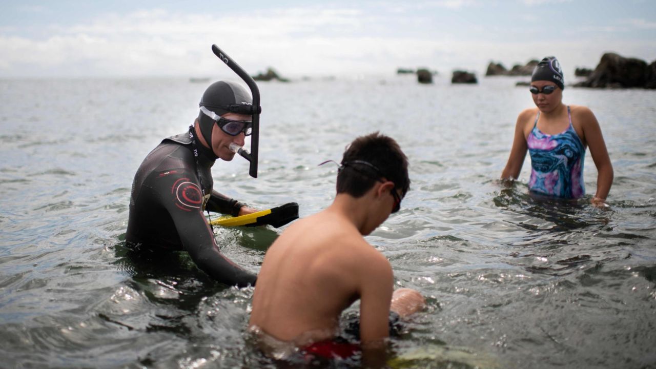 French swimmer Benoit Lecomte begins his attempt of swimming across the Pacific Ocean in Choshi, Japan on June 5, 2018, surrounded by his children.