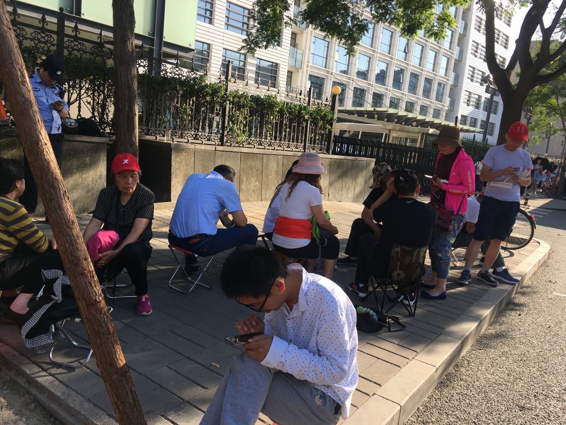 Parents and students endure the hot weather as they wait outside the Ministry of Education in Beijing.