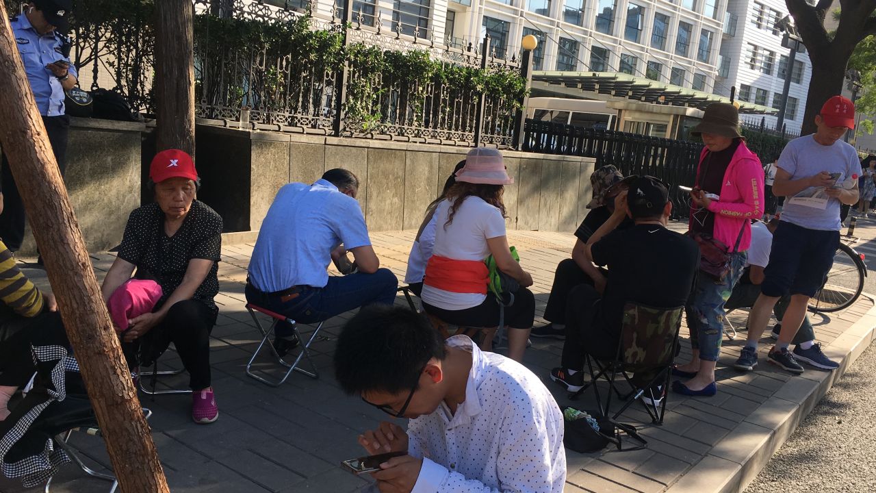 Parents and students endure the hot weather as they wait outside the Ministry of Education in Beijing.