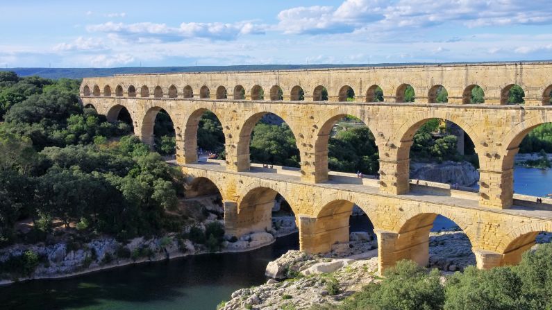Le Pont Du Gard is an ancient Roman aqueduct bridge that crosses the Gard river in southern France. Built by the Romans in the 1st century AD, the bridge has three levels of arches and formerly carried an estimated 44 million gallons of water a day to the city of Nimes.