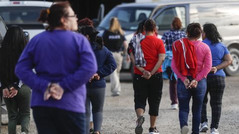 Government agents lead suspects in custody toward a restroom during an immigration sting at Corso's Flower and Garden Center on Tuesday in Castalia, Ohio.
