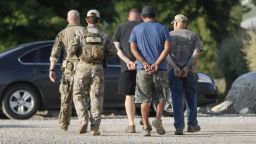 Government agents take suspects in custody during an immigration sting at Corso's Flower and Garden Center, Tuesday, June 5, 2018, in Castalia, Ohio. The operation is one of the largest against employers in recent years on allegations of violating immigration laws.  (AP Photo/John Minchillo)