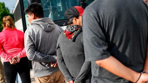 Suspects wait to be loaded onto a bus during an immigration sting at Corso's Flower and Garden Center, in Castalia, Ohio, earlier this month. (AP Photo/John Minchillo)