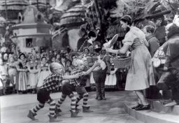 Jerry Maren, center, playing a Lollipop Guild Member, presents Judy Garland with a lollipop in the film 'The Wizard of Oz.'