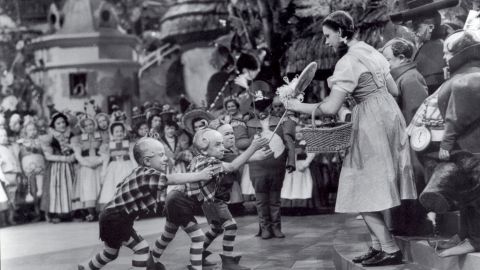 Jerry Maren, center, playing a Lollipop Guild Member, presents Judy Garland with a lollipop in the film 'The Wizard of Oz.'