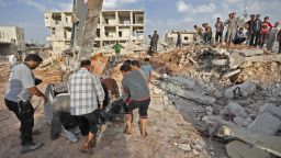 Syrian rescuers and civilians recover bodies in Zardana, in the mostly rebel-held northern Syrian Idlib province, in the aftermath of air strikes in the area, on June 8, 2018. - Air strikes in northwestern Syria, thought to have been carried out by regime ally Russia, killed 38 civilians including four children, a Britain-based monitor said. The raids, which hit a residential zone in the area of Zardana in the northwestern province of Idlib, also wounded 50 people, the Syrian Observatory for Human Rights monitoring group said. (Photo by OMAR HAJ KADOUR / AFP)        (Photo credit should read OMAR HAJ KADOUR/AFP/Getty Images)