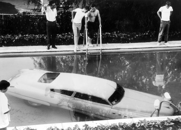 A 1961 image shows a car submerged in a California swimming pool. It is understood that the inebriated driver believed the pool to be a parking space.