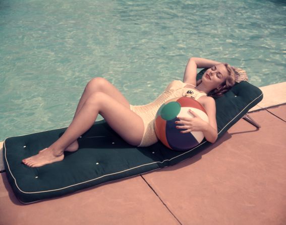 A woman in the 1950s sunbathes by a pool in an image by the American photographer H. Armstrong Roberts. 