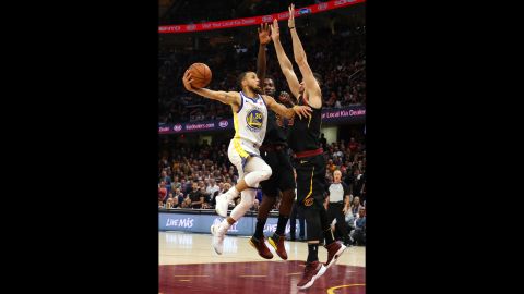 Curry tries to shoot over two Cleveland defenders in the first half of Game 4. Curry had 20 points for the Warriors in the first half, and he finished with a game-high 37.