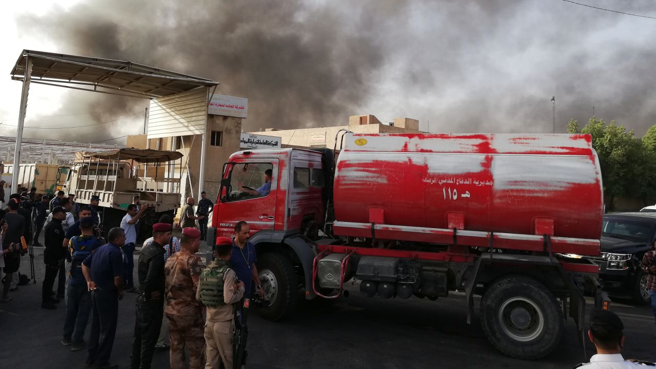Iraqi security forces and firemen gather as smoke rises from a fire that broke out at Baghdad's largest ballot box storage site, where ballots from Iraq's May parliamentary elections are stored, in Baghdad, Iraq, Sunday, June 10, 2018. The ballots are part of a manual recount of votes, mandated in a law passed by the Iraqi parliament last Wednesday. (AP Photo/Karim Kadim)