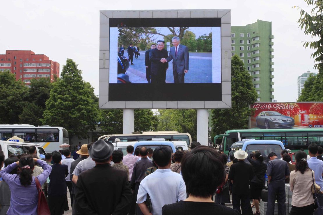 People watch video of Kim Jong Un's arrival in Singapore on a large screen outside Pyongyang's main train station.
