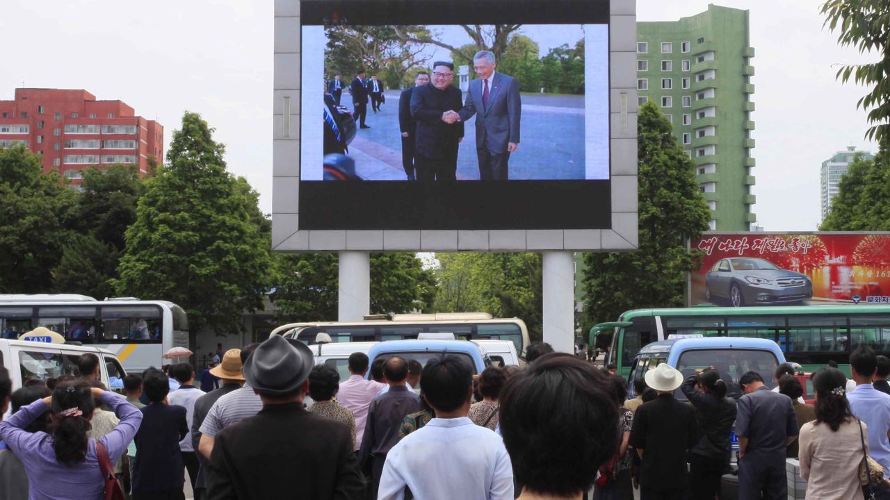 People watch video of Kim Jong Un's arrival in Singapore on a large screen outside Pyongyang's main train station.
