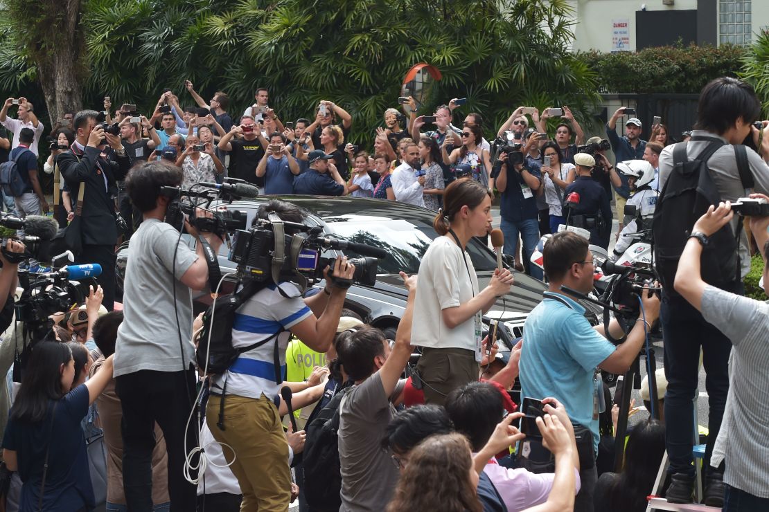 Journalists and onlookers watch the motorcade carrying North Korean leader Kim Jong Un as it arrives at the St. Regis hotel.