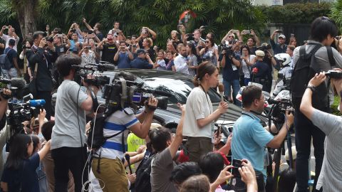 Journalists and onlookers watch the motorcade carrying North Korean leader Kim Jong Un as it arrives at the St. Regis hotel.