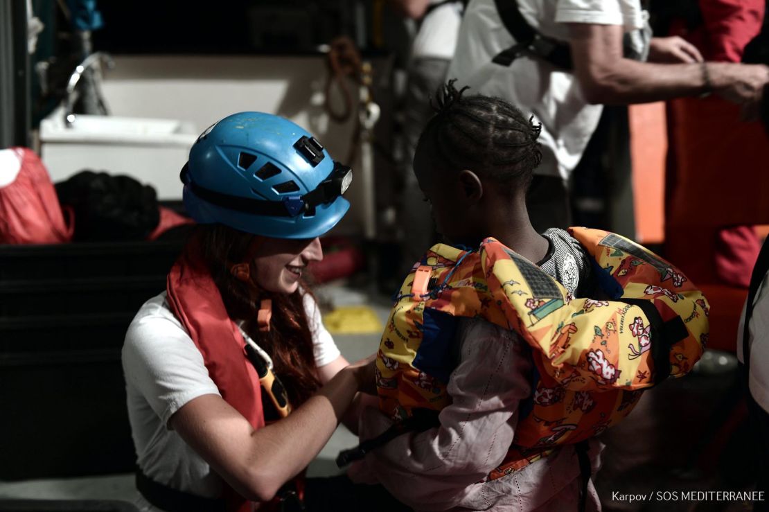 A rescue worker helps a young child on board the Aquarius.