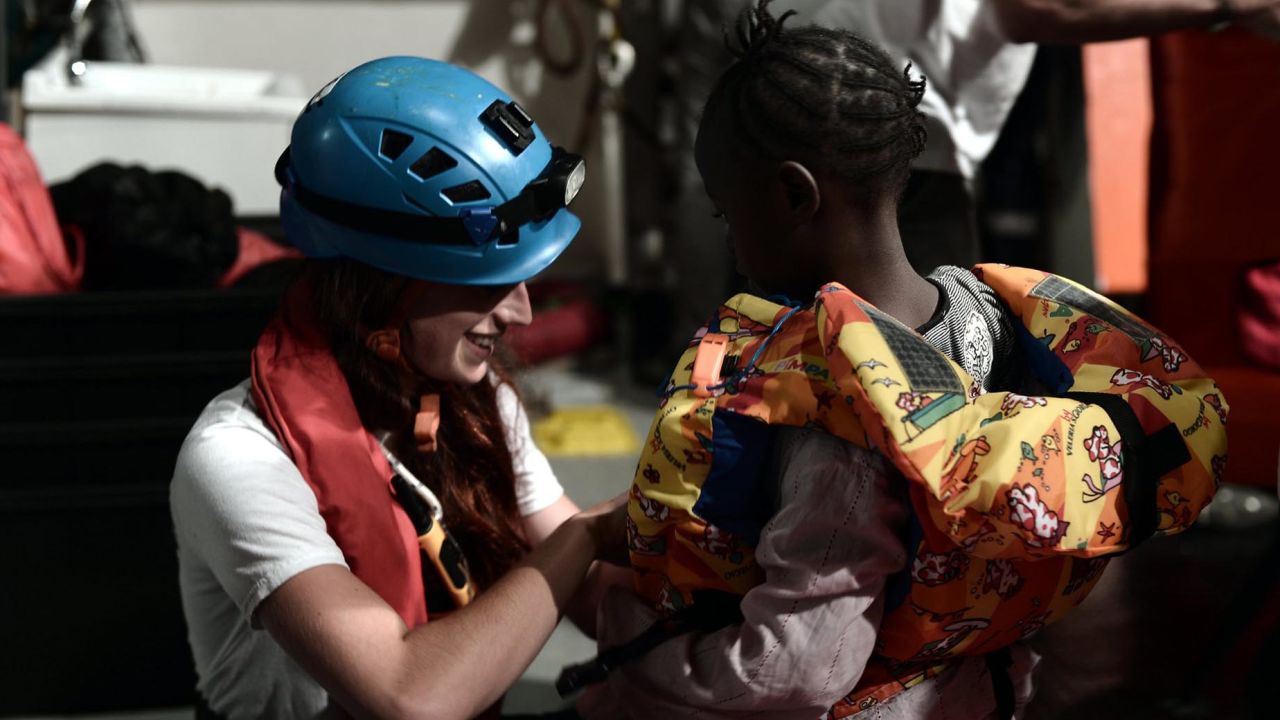 A rescue worker helps a young child on board the Aquarius.