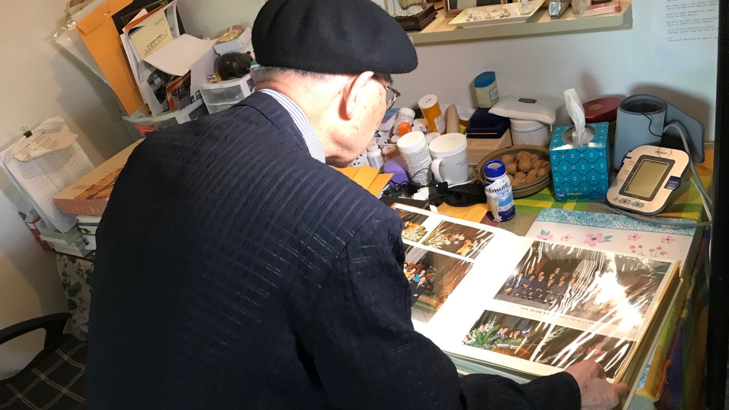 Kyung Joo Lee looks back at a photo album, showing other Korean Americans, many of whom were separated from their families during the Korean War (1950-53) . 