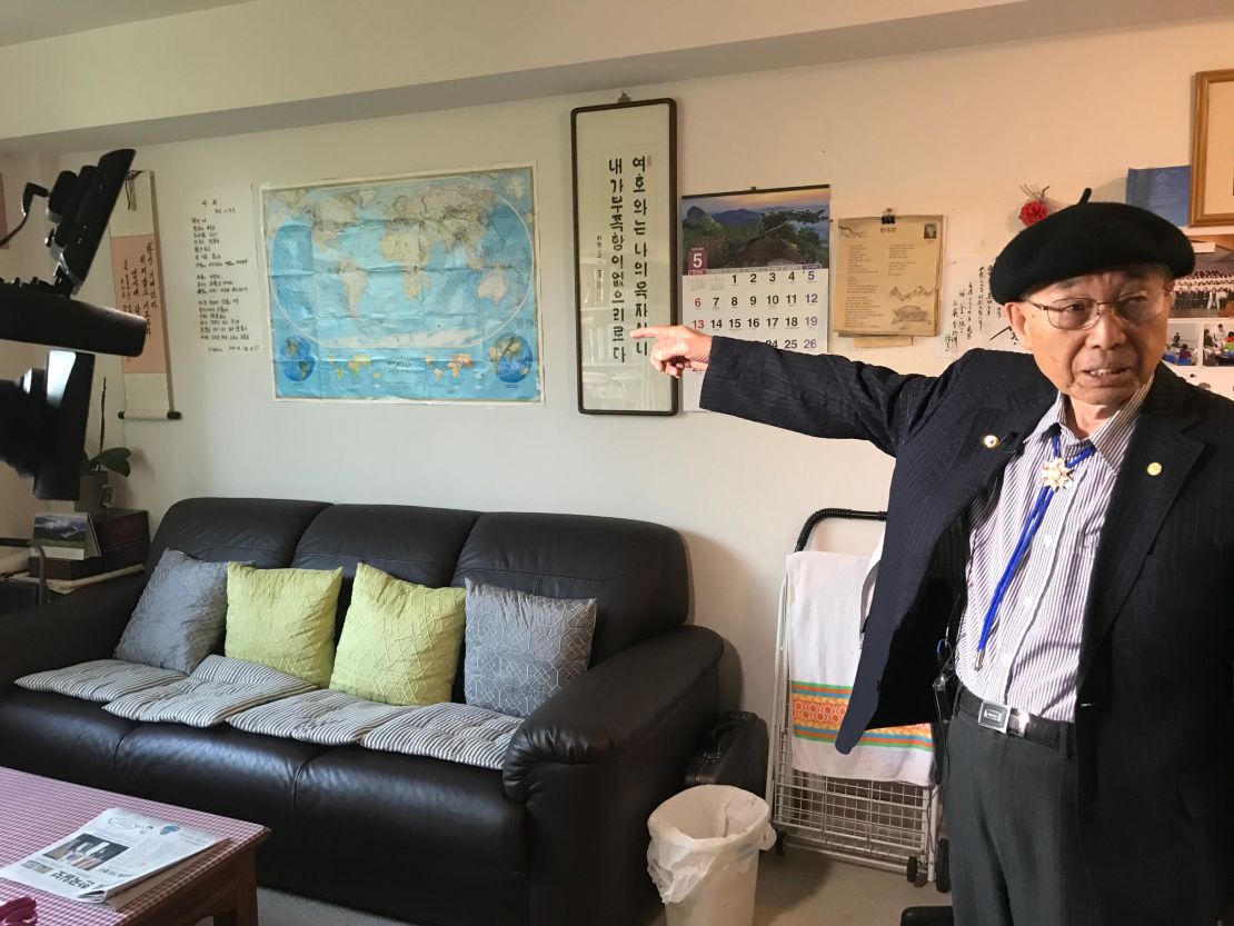 Kyung Joo Lee in his apartment in Virginia, points at a map of the world.