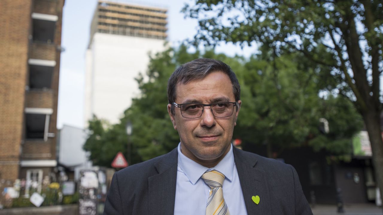 Survivor Miguel Alves wearing a commorative green heart in front of Grenfell Tower.