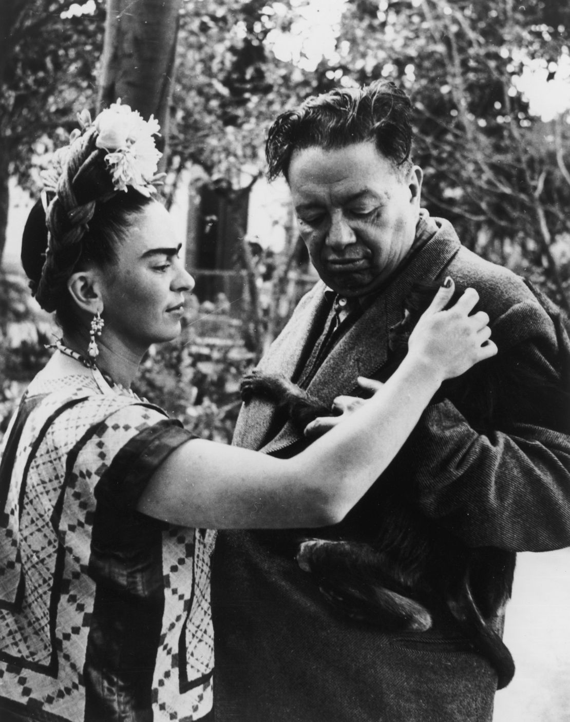 Frida Kahlo pets a monkey clinging to the jacket of her husband, Diego Rivera.