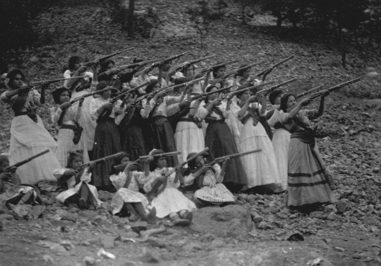 A group of rebel women and girls wearing traditional dress practice their shooting skills for the Mexican Revolution in 1911.