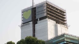 A banner reading "Grenfell Forever in our Hearts" hangs over scaffolding at Grenfell Tower on June 6, 2018.