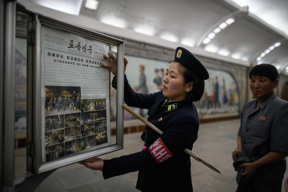 A railway employee puts up the front page of a state-owned newspaper Tuesday, telling news of North Korean leader Kim Jong Un's visit to Singapore.