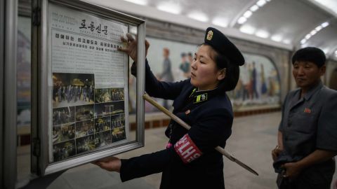 A railway employee puts up the front page of a state-owned newspaper Tuesday, telling news of North Korean leader Kim Jong Un's visit to Singapore.