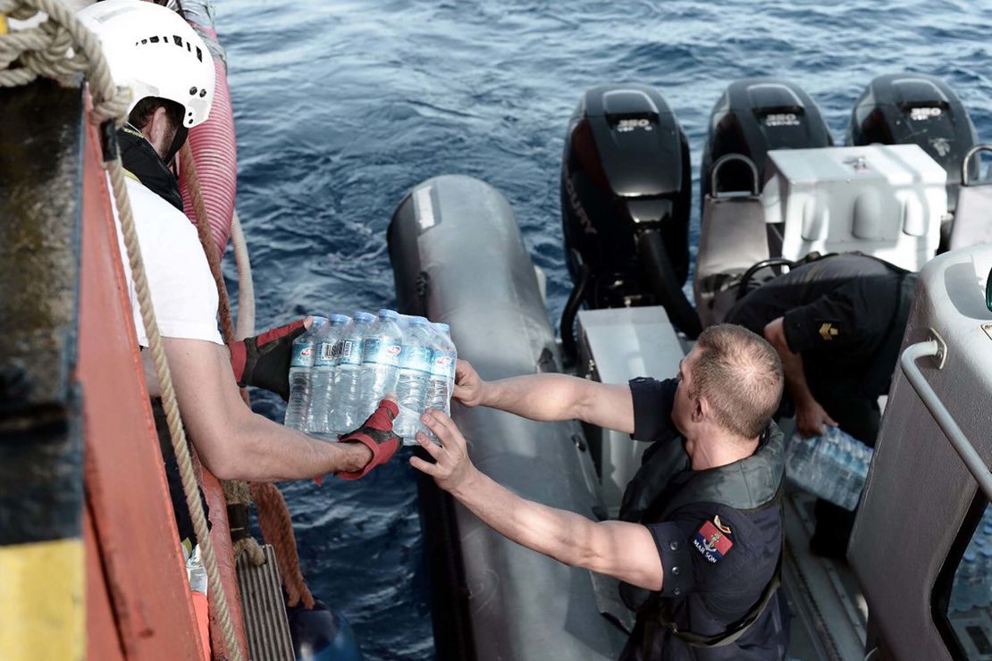 A Maltese maritime officer distributes packs of water to the stranded ship. 