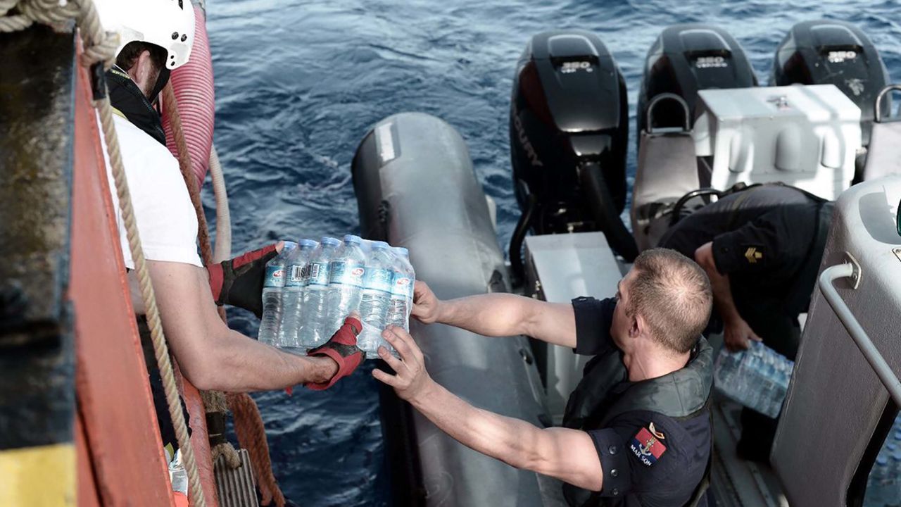 A Maltese maritime officer distributes packs of water to the stranded ship. 