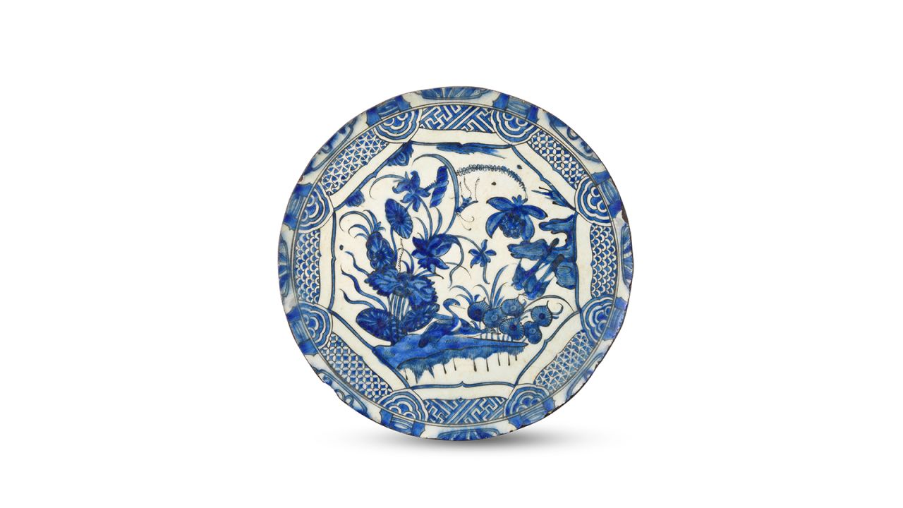 A blue and white dish produced in 17th century Persia depicts diving waterfowl amid plants and flowers. It is an example of "fritware," a type of pottery made from powdered glass.