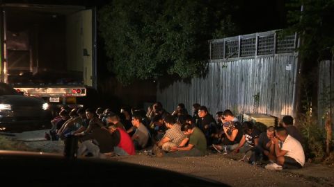 Undocumented immigrants found in an 18-wheeler truck sit while being detained by authorities.