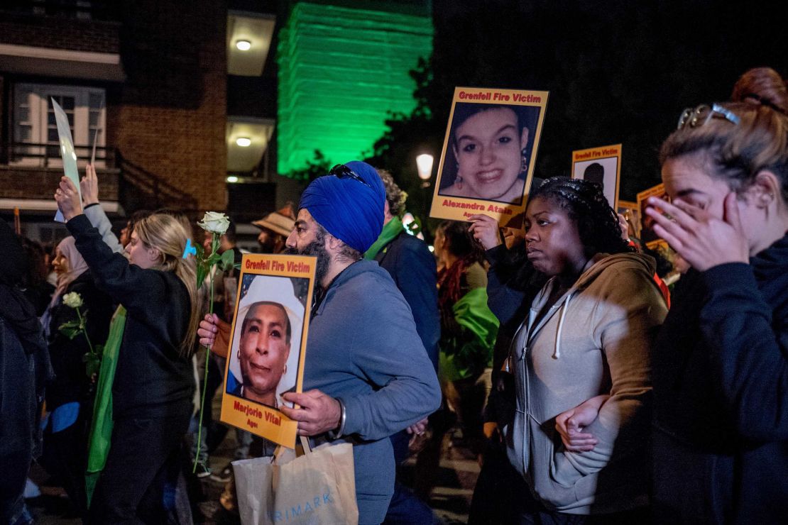 Families and friends who lost loved ones in the fire hold portraits of victims as they march to the illuminated Grenfell Tower in the early hours of Thursday.