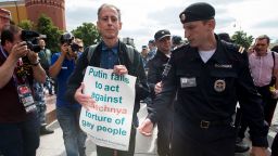 Russian police detane Gay rights activist Peter Tatchell, center, as he holds a banner that read "Putin fails to act against Chechnya torture of gay people" near Red Square in Moscow, Russia, Thursday, June 14, 2018. A British LGBT activist has been detained has been detained near the Red Square for holding a one-man protest against Russia's abuse of gays. (AP Photo/Alexander Zemlianichenko)